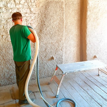 Artisan projetant un mélange chaux chanvre pour isoler un mur